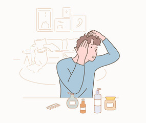 A man arranging beauty products in front of him and examining the condition of his hair.