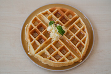 Top view of homemade waffles with syrup in plate on wooden table, top view. 