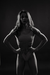 Naklejka premium Beautiful young sporty muscular woman, isolated against dark background