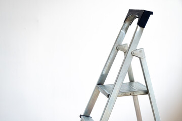 Stepladder against a white wall. Place for your text. Renovation concept in the room.