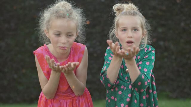 two beautiful little girls playing with confetti in front of the camera - people having fun in slow motion