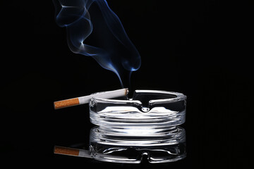 Cigarette and ash tray on dark background