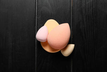 Makeup sponges on dark wooden background