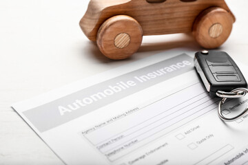 Automobile insurance with key and car figure on white wooden background, closeup