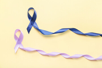Lilac and blue ribbons on color background. Cancer awareness concept