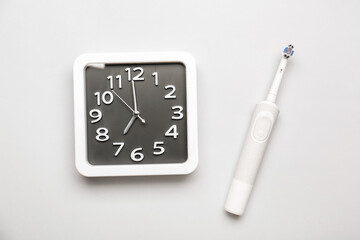 Stylish clock and tooth brush on light background