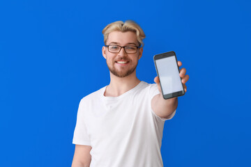 Handsome man with mobile phone on color background