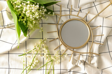 Beautiful lily-of-the-valley flowers and mirror on light fabric