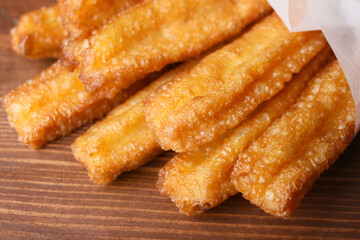 Tasty churros on wooden background, closeup