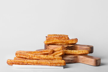 Boards with tasty churros on white background