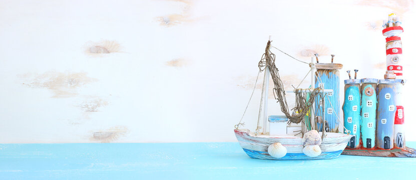 Nautical concept with sea life style objects as boat, driftwood beach houses and seashells over wooden background