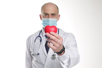 Young doctor wearing a mask with stethoscope and red heart isolated over white background