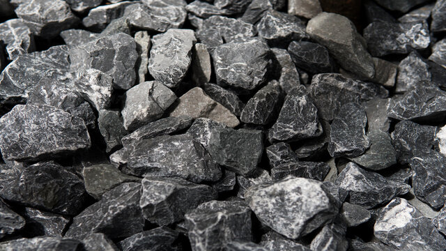 Closeup Pile of Crushed grey stone charcoal color or road metal texture background with natural sunlight