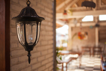 A street lamp inside a spacious romantic house interior. A metal and glass vintage lantern on a brick wall of an old fashioned mansion.