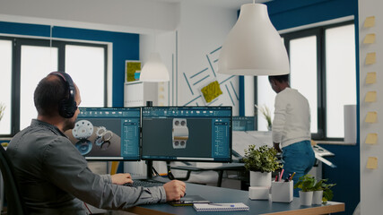 Mecanic technician working on cad software using computer with two monitors innovating an efficient...