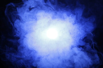 Artificial magic smoke in blue light on black background
