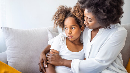 Focus on upset sad small daughter sitting on sofa with mother, mom scold kid for bad behaviour,...