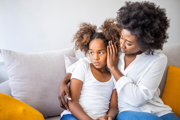 Focus on upset sad small daughter sitting on sofa with mother, mom scold kid for bad behaviour, child psychologist help girl deal with emotional social behavior problems trauma therapy support concept