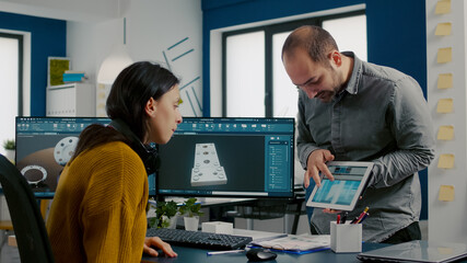 Industrial designer discussing with colleague holding tablet with in CAD program, designing 3D prototype of building. Woman engineer using pc with two monitors sharing ideas for construction mechanism - obrazy, fototapety, plakaty