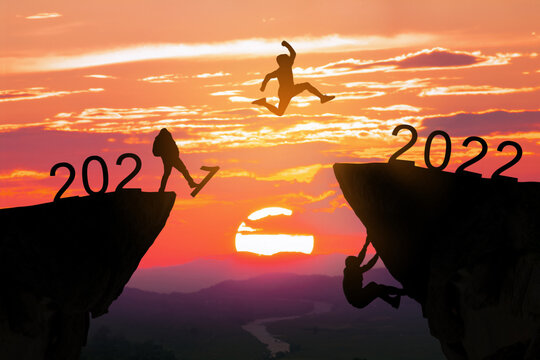 Concept Happy new year 2022 Silhouette image of happy man jump from 2021 up to 2022 on beautiful sky sunrise, copy space for text.