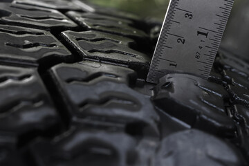 Car care staff using a steel ruler check and measurement tire tread depth with blurred old car...