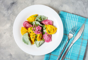 Multi colored dumplings from color dough stuffed with meat on concrete background.