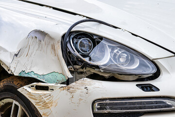 Broken car after a crash. Damaged wing and headlamp of a car, scratches on a car body.