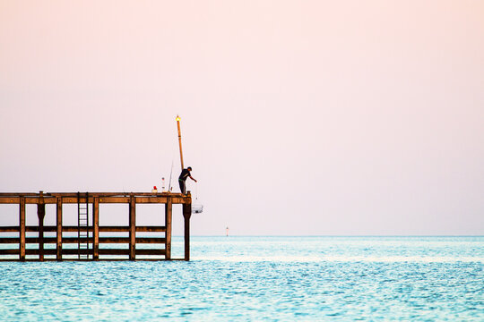 Fisherman lowering a crab pot from jetty in Wallaroo