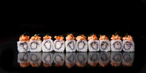 japanese rolls with sauce in a row on a black background