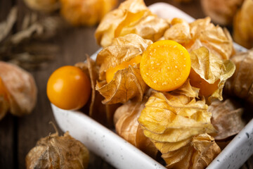Cape Gooseberry in a white cup rests on an old wood floor