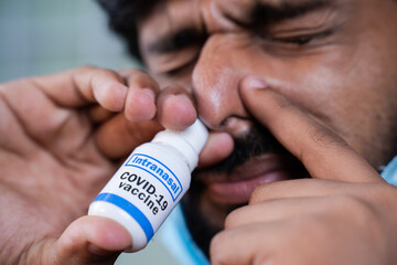 Extreme close up of Young man with medical face mask inhales coronavirus covid-19 nasal vaccination spray to protect from virus infection - obrazy, fototapety, plakaty