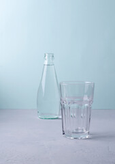 An empty glass on a blue background. Background blurred glass bottle, selective focus, copying space