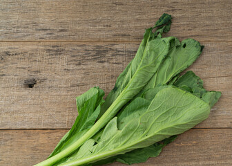 Withered mustard green on shabby wooden board.