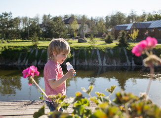 Cute preschooler child holding a plastic bottle with yogurt. The boy got hungry for a walk in the...