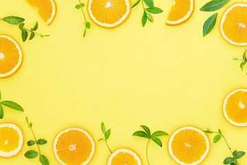 Summer bright background with oranges and green leaves on the yellow surface and place for text in the middle	
