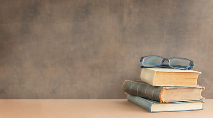 Back to school and education concept. Stack of books and glasses on the top near the blackboard and place for text.