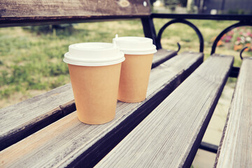 Two cups coffee to take away in park on wooden bench
