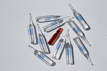 a red medical ampoule and several transparent ones on a white background