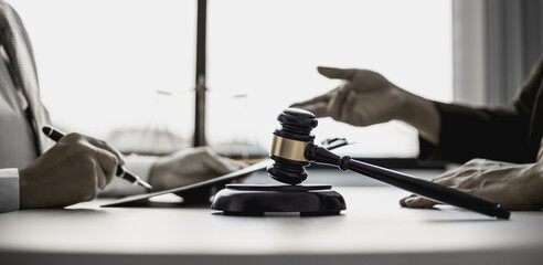 A small court judge's hammer is placed on the lawyer's table, the lawyer is advising the client to help them win the case against the defendant. The concept of litigation counseling for clients.