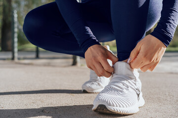 Close up of young woman tying laces on her sports shoes