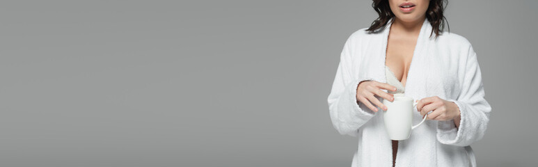 Cropped view of sexy woman in bathrobe holding cup of coffee isolated on grey, banner