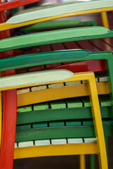 Closeup details of stacked multicolored wooden chairs near closed cafe