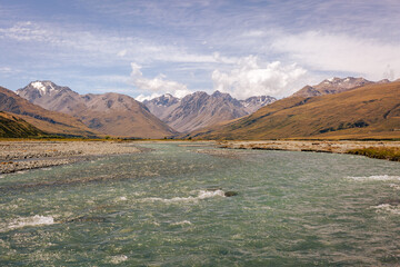 View of the shallow, swiftly flowing mountain river. In the background a mountain range with...