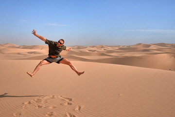 happy man jumping for fun enjoying desert adventure travel