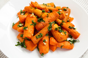 Homemade Roasted Carrots with Herbs on a white plate, side view. Close-up.