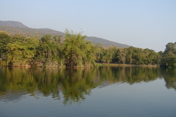Lake among tropical nature. Green trees, calm water surface
