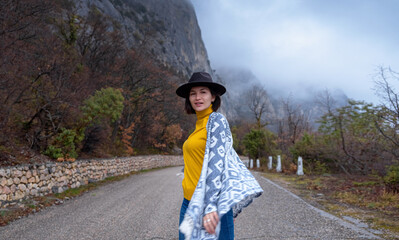 Stylish hipster woman in a hat walking down a mountain road