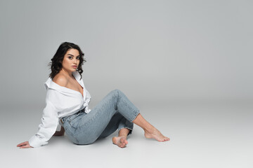 Seductive woman in white shirt posing on grey background