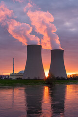Nuclear power plant against sky by the river at sunset