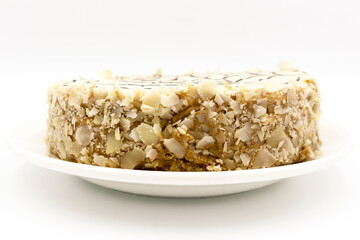 Cake with white cream and chocolate dressing in the form of a spiderweb, and a sprinkle of almond chips on a white plate